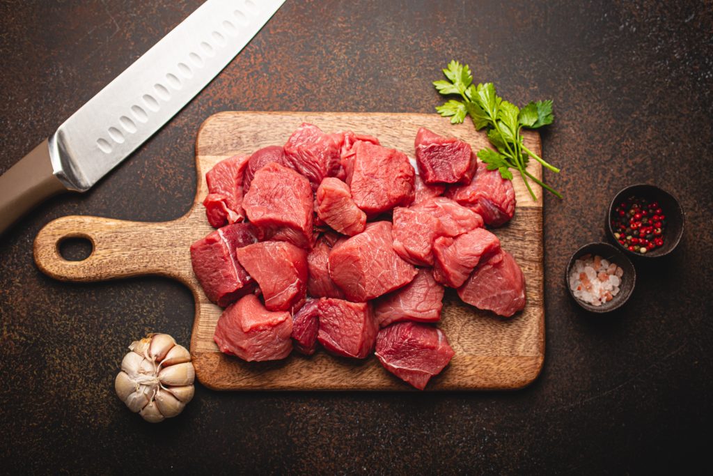 Pieces of Meat with a carving knife on a board with seasoning