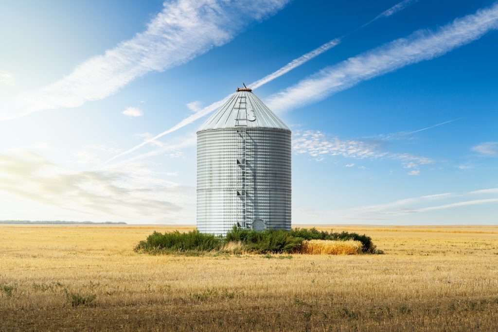 Grain bin in empty wheat field 
